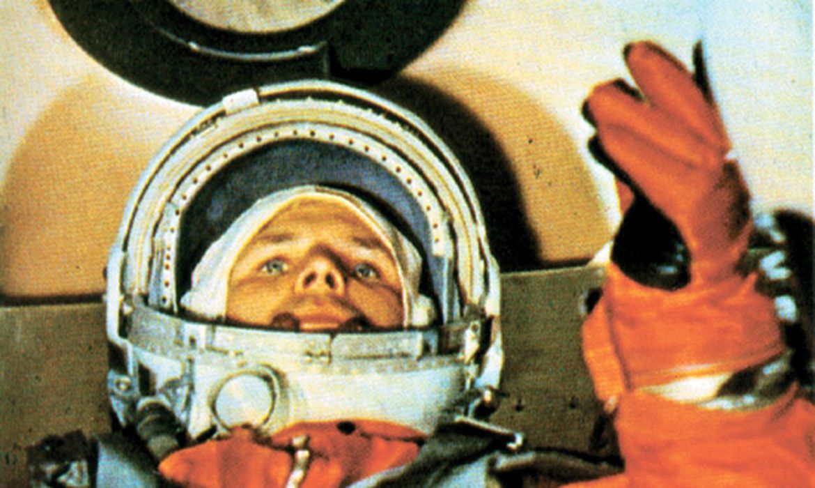''Blue moon / you saw me standing alone'' (“lua azul / você me viu de pé, sozinho”, em tradução livre). Dia 12 de abril de 1961: data em que a regravação da canção Blue Moon, pela banda The Marcels, chegou ao topo das paradas de sucesso dos Estados Unidos, segundo sites especializados. Enquanto os americanos faziam referências românticas à Lua, neste mesmo dia, a União Soviética entrava para a história com o lançamento do primeiro homem à órbita do planeta Terra. Sem anúncios oficiais, há exatos 60 anos, o major da Força Aérea russa Iuri Gagarin, de 27 anos, entrou a bordo de uma cápsula de 2,3 metros – batizada de Vostok 1 – e, em um voo de uma hora e 48 minutos, deu uma volta ao redor do planeta. “Vejo a Terra. Ela é azul”, disse Gagarin, em respostas fragmentadas, via rádio, ao comando russo em terra. Ao voltar ao chão, ileso, Gagarin virou uma das principais referências da corrida espacial ao longo das gerações. A comemoração em torno do feito daquele 12 de abril tomou conta da programação da rádio no país e das ruas de Moscou. Acabou dando origem a um feriado do país desde 1962: o Dia do Cosmonauta. Em um período marcado pela Guerra Fria e pela expectativa de domínio político e de tecnologias via conquistas espaciais, a então URSS dava um passo largo, pouco tempo depois do lançamento do satélite Sputnik, em 1957. ''É possível sonhar com algo maior?'', retoricamente perguntou Gagarin, dirigindo-se aos russos após o sucesso da missão Vostok. O acontecimento histórico acirrou o empenho dos Estados Unidos e, menos de um mês após o voo de Gagarin, em 5 de maio de 1961 o primeiro norte-americano foi lançado à órbita da Terra: Alan Sheperd. Oito anos depois a Agência Espacial Norte-Americana (Nasa) saiu à frente ao levar o primeiro homem à Lua – ao que Iuri Gagarin, que morreu em 27 de março de 1968, aos 34 anos, durante um voo de treinamento, não pode assistir. De camponês, operário, até chegar a aviador, o cosmonauta Gagarin definiu sua contribuição por ter pavimentado o caminho do homem no espaço. Estrada seguida por Neil Armstrong ao pisar na Lua, entre outros, e com expectativa de marcha acelerada rumo à Marte, em um futuro próximo. Um herói de todas as gerações Em nota à Agência Brasil, a Embaixada da Rússia no país lembrou a importância de Gagarin para a humanidade. “É um homem que abriu espaço para os seus contemporâneos, realizou o sonho atrevido e fantástico acalentado há séculos, mostrou às pessoas que nada é impossível. É um herói de todas as gerações não só para a Rússia, mas para todo o mundo'', destaca. Cosmodrome Space Flight Airfield on April 12th 1961 Space pilot Yuri Gagarin takes the bus to the Iuri Gagarin foi camponês e operário antes de tornar-se aviador e cosmonauta. Ele morreu aos 34 anos, durante um voo de treinamento - Foto: Imago Images/Direitos reservados Este ano, em decorrência da pandemia do novo coronavírus, as celebrações pelo 12 de abril na Rússia se restringirão a uma cerimônia na Plataforma de Gagarin (local de onde a Vostok foi lançada, em 1961) e uma conferência com delegações estrangeiras, que contará com a presença do primeiro-ministro do Cazaquistão, Askar Mamin. Além disso, uma coroa de flores será colocada no Kremlin em homenagem aos cosmonautas mortos. O país também destaca, neste feriado nacional, a adoção de tecnologias inovadoras em pesquisas espaciais. Na última sexta-feira (9) um voo tripulado, em homenagem a Gagarin, foi levado à Estação Espacial Internacional, com dois cosmonautas russos e um americano. De acordo com a embaixada, com a construção do novo cosmódromo Vostochny, novos equipamentos estão sendo desenvolvidos para projetos, como a nave tripulada Orel, o veículo de lançamento Irtysh e o propulsor de foguetes RD-171MW, considerado o mais potente do mundo. Sobre as parcerias Brasil-Rússia na área espacial, a embaixada ressalta a cooperação no monitoramento do geoespaço e de asteroides potencialmente perigosos para a Terra. Lembra ainda o recente lançamento do nanossatélite, NanossatC-BR2, do cosmódromo de Baykonur, em março e também a ida à Estação Espacial Internacional, há 15 anos, a bordo de nave russa, do astronauta e atual ministro da Ciência, Tecnologia e Inovações, Marcos Pontes. Da polarização à democratização do espaço Passado o período de polarização da corrida espacial, atualmente os Estados Unidos também contam com a base de lançamento controlada pela Rússia para enviar astronautas ao espaço, devido ao fim do programa de ônibus espaciais da Nasa, em 2011. Para o diretor do Instituto Nacional de Pesquisas Espaciais (Inpe), Clezio Marcos de Nardin, 60 anos após o primeiro voo na órbita da Terra, hoje o acesso ao espaço se dá por vários países e com diversas finalidades. “Nós temos acesso do espaço para uso civil e militar, a finalidade última desde a época dos EUA e URSS, e continua com outros países, com toda Europa entrando no sistema, o Japão, China, Índia e o Brasil, com a Missão Espacial Brasileira Completa e a base de lançamentos em Alcântara, no Maranhão. Falei dos principais, mas também cito Argentina, Colômbia, Chile, México e Peru”, destaca. Diversos setores têm interesse em "ocupar" o espaço, segundo Clezio, utilizando-o em prol da cidadania e para fins pacíficos: telecomunicações, meteorologia, geoposicionamento, agricultura de precisão, e cada vez mais, a presença do ''cidadão, entrando como usuário de sistemas guiados por satélites'', diz. Para o diretor do Inpe, as parcerias entre os países são essenciais, mas este ainda é um setor que envolve disputas – econômicas e tecnológicas. “Quem domina esta tecnologia domina um setor de mercado estratégico para o desenvolvimento das nações", pondera. ''O Inpe vê com muitos bons olhos as parcerias internacionais no setor espacial, e do ponto de vista econômico e científico, a Rússia sempre foi um parceiro do Brasil'', ressalta. Do voo de Gagarin ao legado para as gerações futuras, Clezio destaca o desafio do esforço empreendido pelas gerações passadas e também pela presente, na construção de ''uma sociedade melhor, mais justa, mais democrática do ponto de vista do conhecimento, com mais acesso inclusive aos serviços derivados dos programas espaciais''.