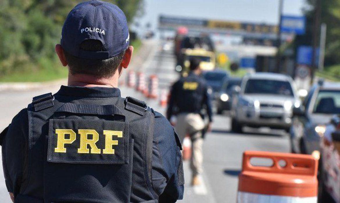 A Polícia Rodoviária Federal (PRF) reforçará, de hoje (12) até a próxima terça-feira (16), o policiamento ostensivo próximo aos pontos das rodovias federais onde mais são registrados acidentes graves e ocorrências criminosas. A intensificação da fiscalização faz parte da Operação Proclamação da República 2021 e visa a inibir infrações de trânsito, como excesso de velocidade, ultrapassagens indevidas e proibidas, transitar pelo acostamento e motoristas dirigindo embriagados. Como de costume, o feriado prolongado (Proclamação da República, 15 de novembro) deve motivar o aumento do número de veículos nas estradas, potencializando os riscos de acidentes. Assim, além de ampliar o efetivo policial de serviço e intensificar as rondas ostensivas, principalmente durante os horários de maior movimento, a PRF orienta quem vai pegar a estrada a estar atento às boas condutas, como revisar o veículo, com especial atenção para o funcionamento dos equipamentos obrigatórios. E, em caso de acidentes ou incidentes, o motorista deve ligar para o telefone de emergência 191. Distância segura Também é importante verificar a documentação do veículo e de todos os ocupantes, inclusive de crianças e adolescentes. Durante o percurso, o motorista deve manter uma distância segura do veículo à frente, respeitando os limites de velocidade estabelecidos para a via, e trafegando com os faróis acesos, mesmo durante o dia. E, quando necessário, ultrapassar apenas pela esquerda. A Polícia Rodoviária Federal também lembra a necessidade de os motoristas estarem atentos a pedestres, ciclistas e outros usuários, sobretudo próximo aos núcleos urbanos. As ações preventivas também visam reduzir a gravidade dos eventuais acidentes e serão focadas em pronto atendimento, de forma a garantir fluidez ao trânsito. Além dos agentes de prontidão nas rodovias, policiais federais monitorarão o comportamento dos motoristas a partir das Centrais de Comando e Controle, de onde podem acompanhar, em tempo real, por meio de câmeras, tudo o que acontece ao longo das estradas, flagrando ultrapassagens indevidas ou proibidas; veículos trafegando pelo acostamento ou desenvolvendo velocidades incompatíveis com a via.